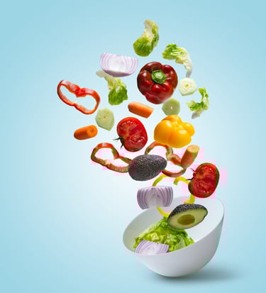 a bowl of vegetables being tossed in a bowl