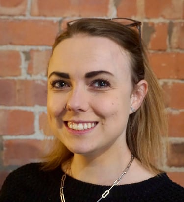 Coach Moll - a woman in her thirties with glasses and a black sweater