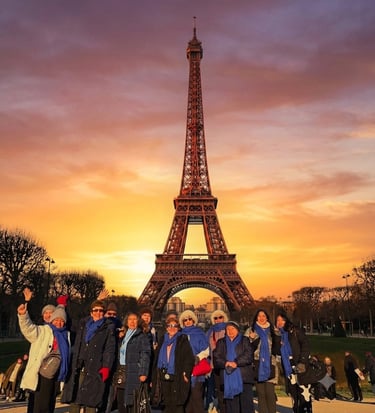 Un grupo de turistas con bufandas azules posan frente a la Torre Eiffel durante una puesta de sol.