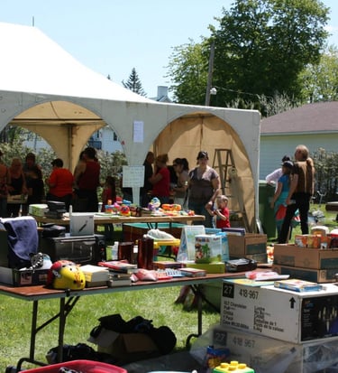 a group of people standing around a table with many items