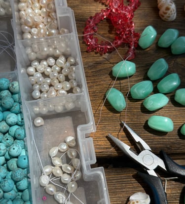 Jewelry making tools and supplies including freshwater pearls, turquoise beads, and needle nose pliers.