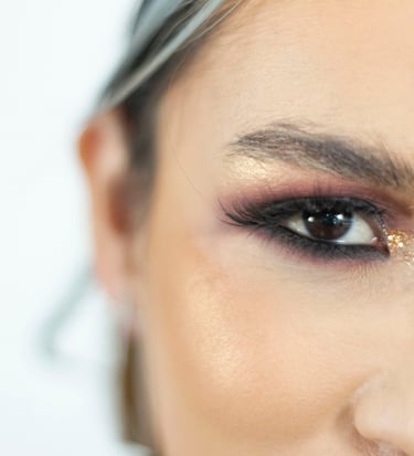 Primer plano de un glamoroso maquillaje de ojos con brillo dorado, sombra de ojos ahumada y pestañas