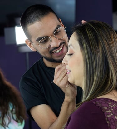 Maquillador profesional masculino con gafas aplicando cosméticos faciales a una mujer sonriente