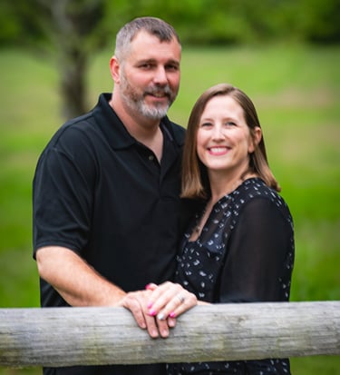 Smiling couple posing for an outdoor portrait by a wooden fence at Burr Oak State Park Glouster, Oh