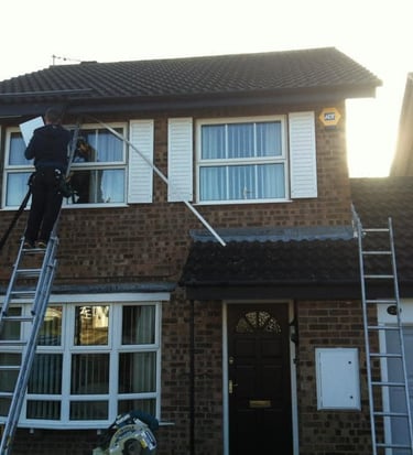 a man on a ladder ladder to reach up to a house