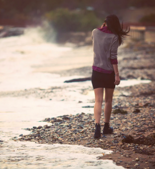 Femme marchant en bord de mer dans un moment de réflexion intérieure
