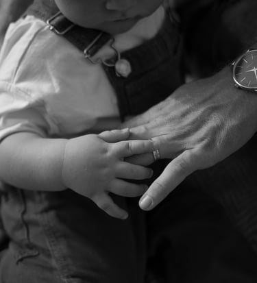 Baby boy playing with hands of his father