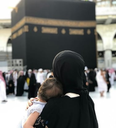 A muslim mother holding her baby while facing the Holy Kaaba in Mecca for pilgrimage.