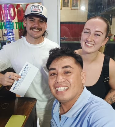 A happy group of travelers posing with a Bali tour voucher at a local travel agency.