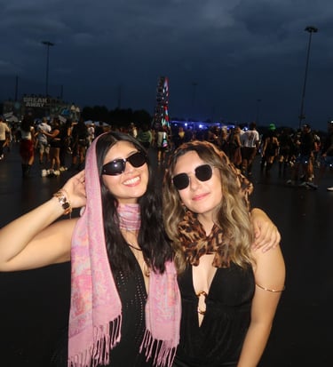 two women in black outfits standing in front of a ferris wheel