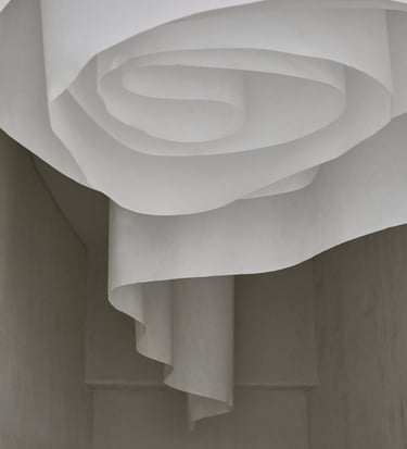 Minimalist white paper art installation with flowing spiral curves in a modern interior.