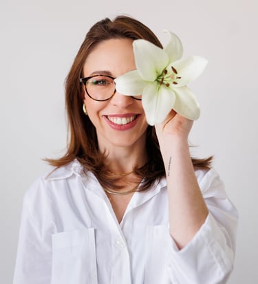 Tatiane amaro segurando uma flor em frente ao rosto.