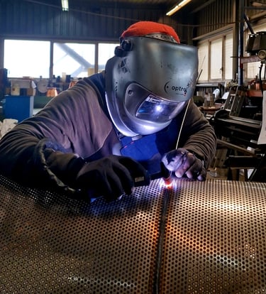 a man in a welding helmet welding a piece of metal