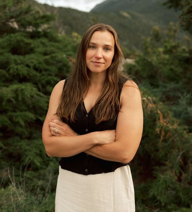 a woman in a white dress standing in front of a mountain