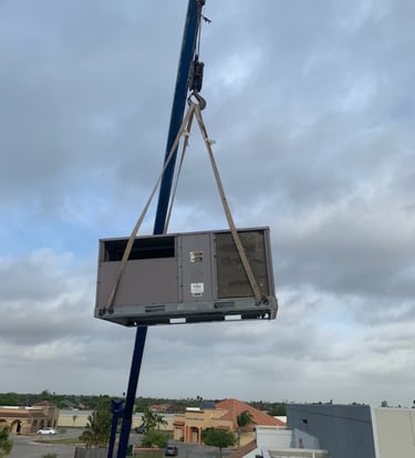 a crane is lifting a ac unit to replace and install