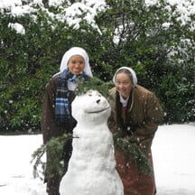 Two Carmelite nuns behind a snow man.