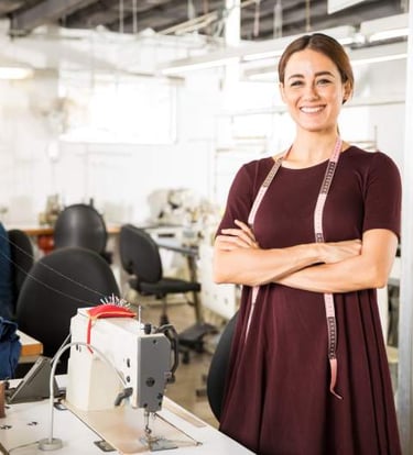 Una diseñadora de moda sonriente, de pie en una fábrica de confección