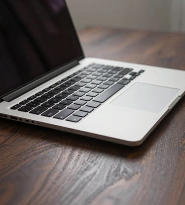 A close-up photograph of a sleek, high-end aluminum laptop on a dark wood desk in a minimalist studio in the North American / US, soft natural lighting highlighting professional design tools.