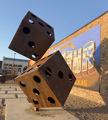 Metal rusted dice statue Decatur Texas mural behind it 