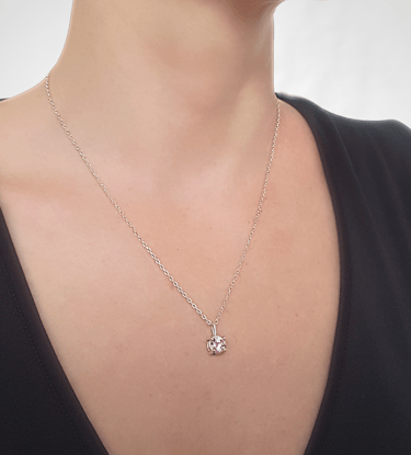 a woman wearing a black top and a necklace with a pink heart