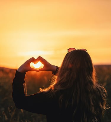 Femme formant un coeur avec ces mains devant un soleil pour etre accompagnée a plonger au coeur