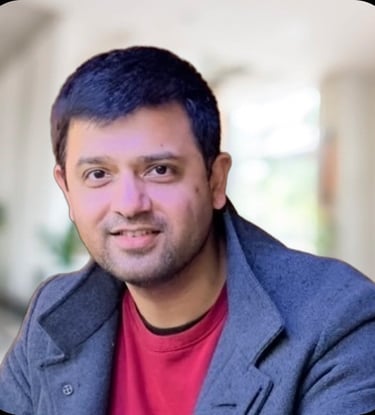 Photo of Kishore Rajendran with a grey jacket and red jumper