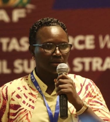 a woman in a yellow shirt and glasses speaking into a microphone