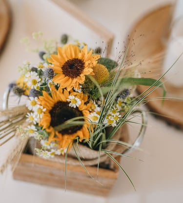 Rustikales Tischgesteck für eine Hochzeit mit leuchtenden Sonnenblumen und Gänseblümchen