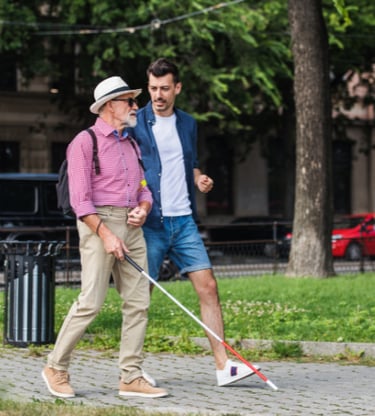 Man with macular degeneration and cane for the blind traveling in a big city