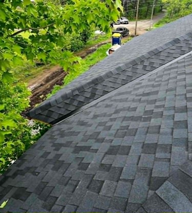 Aerial view of a newly installed asphalt shingle roof with black architectural shingles on a residential home.