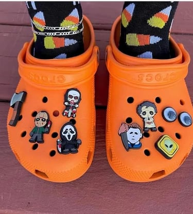 a person wearing orange crocs with halloween charms