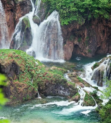 Plitvice Lakes National Park waterfalls cascading into turquoise pools surrounded by forest.