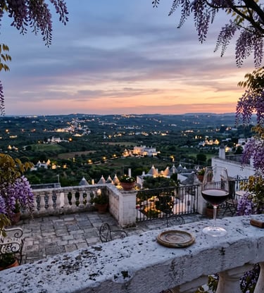 Cisternino panoramic terrace at sunset with Primitivo wine glass and Valle d'Itria view framed by wisteria