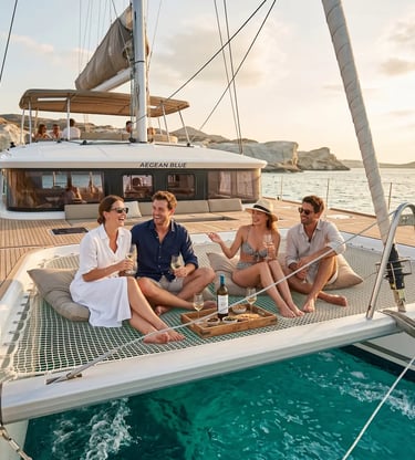 Four travelers enjoying wine on Aegean Blue catamaran bow netting near Kleftiko cliffs Milos