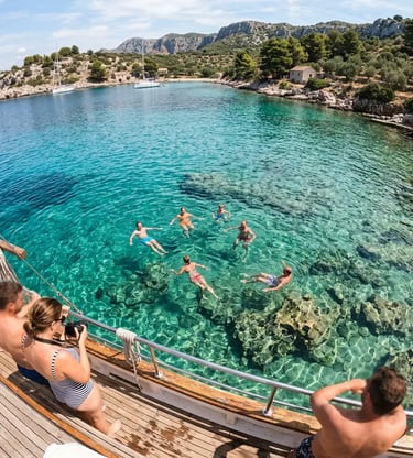Group swimming in crystal-clear turquoise water of Fumija Bay near Split Croatia from boat deck