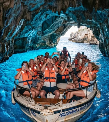 Tourists in life vests taking identical phone photos inside blue sea cave on Polignano boat tour