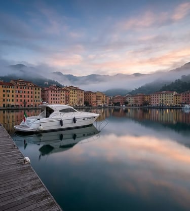 Private boat moored at La Spezia harbor at dawn with misty hills in the background