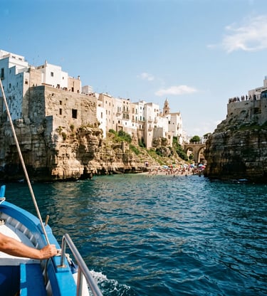 Blue wooden boat approaching whitewashed Polignano a Mare cliffs and Lama Monachile beach.
