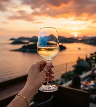 Hand holding Croatian white wine glass against Adriatic sunset over Elaphite Islands Dubrovnik