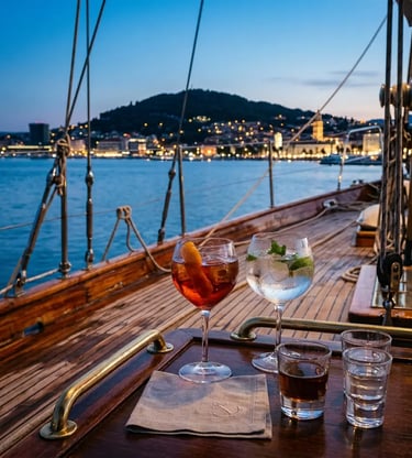 Cocktail glasses on polished sailboat deck with Split Croatia city lights at blue hour