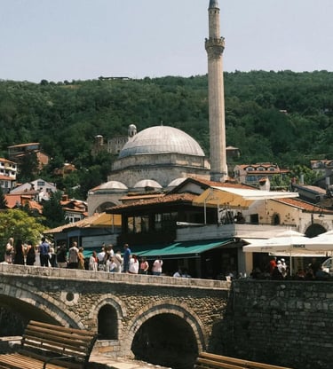Ottoman mosque minaret rising above stone bridge and bazaar in historic Prizren Kosovo