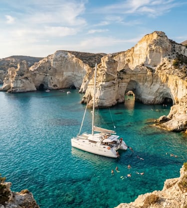 White catamaran anchored at Kleftiko Milos with swimmers in turquoise water below white cliffs