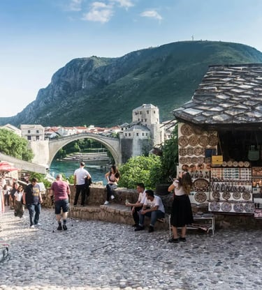 Tourists walking cobblestone streets near Stari Most bridge and souvenir stalls in Mostar Bosnia
