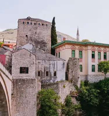 Stari Most stone bridge with medieval tower and colorful Ottoman building in Mostar Bosnia