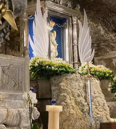 Madonna statue with white angel wings and flowers inside sacred grotto shrine