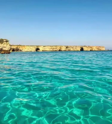 Crystal-clear turquoise Adriatic water and limestone cliffs of Salento coast near Torre dell'Orso