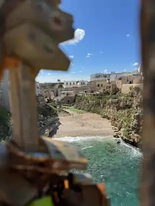 Lama Monachile beach cove in Polignano a Mare seen through bridge love locks
