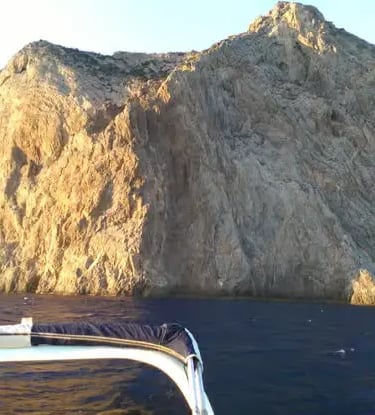 Dramatic limestone cliffs of Capo Teulada seen from a dinghy on the sea