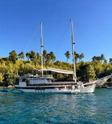 Traditional wooden Gulet boat anchored in a turquoise cove near Split Croatia with pine trees