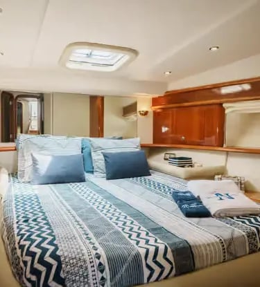 Cozy master cabin on a Douro yacht with double bed, nautical bedding and round porthole.